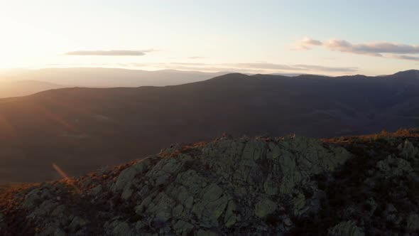 Two people watching sunrise on moutain ridge at El Atatzar dam, Spain