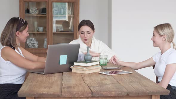 Three beautiful women at home sitting on sofa using a computer and smiling. Indoors, people.