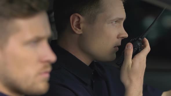 Police Officers on Duty Receiving Call on Two-Way Radio Sitting in Patrol Car