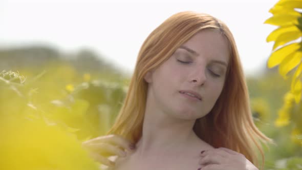 Portrait of Cute Confident Sensual Girl with Red Hair and Green Eyes Standing on Sunflower Field