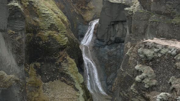 Stream of water falling through rocks at Fjadrargljufur Canyon, Iceland. Aerial