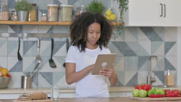 Young African Woman Using Tablet in Kitchen
