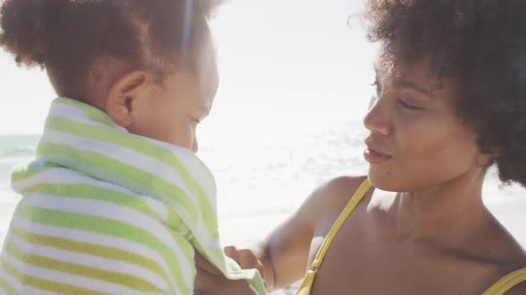 Smiling african american mother toweling off her daughter on sunny beach