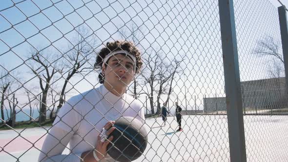 Portrait of a Basketball Player Standing with Ball Near Gread on Basketball Court Slow Motion