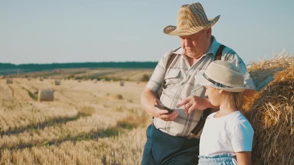 Little Girl with Grandfather in Field Haystacks, Grandfather Farmer Is Teaching the Younger