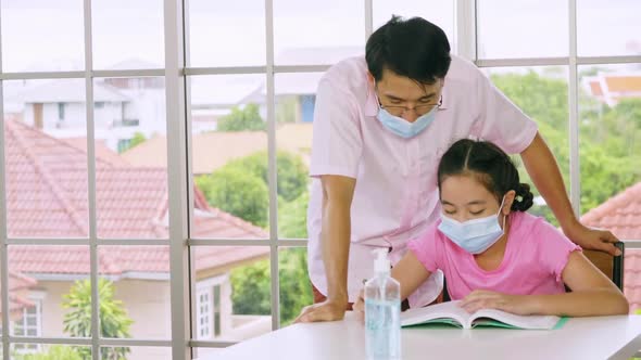 Father is teaching his daughter to do homework while quarantine at home.