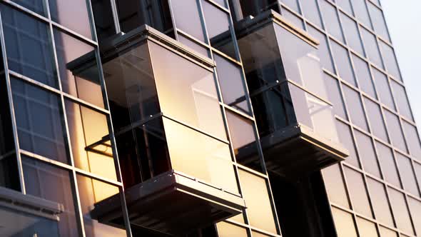 Exterior elevator cabins on a skyscraper glass facade during sunset. 4KHD