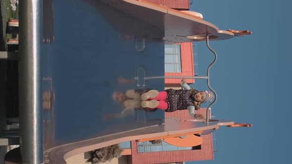 Little Girl Riding Slide on a Playground