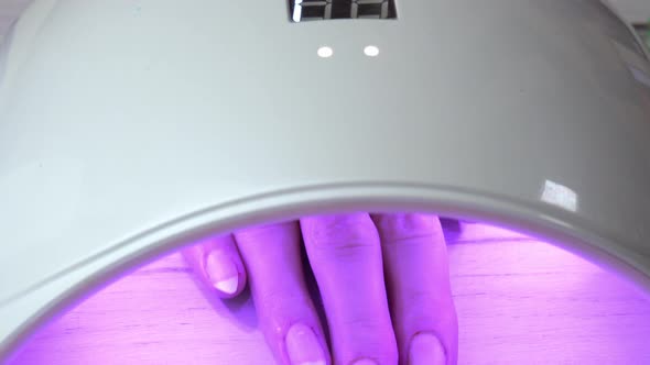 Girl Placed Hand Under an Nail Polish Curing Lamp and Waits for the Nail Polish to Harden