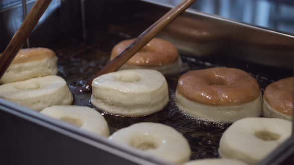 The Chef Is Turning the Donuts on Another Side with Sticks While Frying