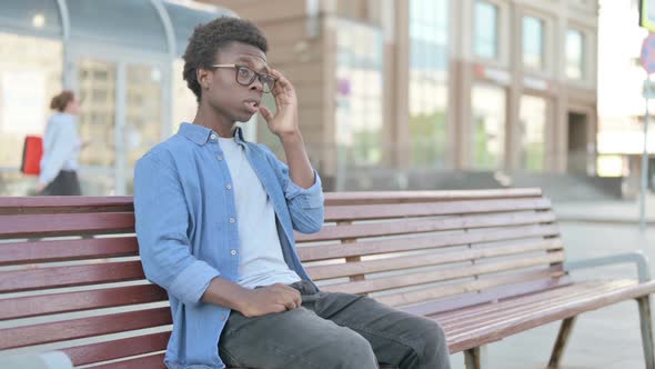 Young African Man with Headache Sitting Outdoor on Bench