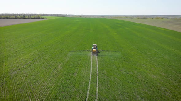 Aerial View of Farming Tractor Spraying on Field with Sprayer, Herbicides and Pesticides at Sunset