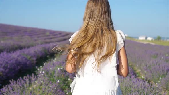 Woman in Lavender Flowers Field at Sunset in White Dress and Hat