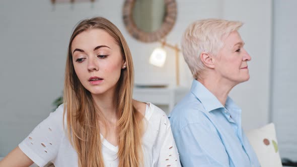 Annoyed Young Adult Daughter and Worried Old Senior Elderly Parent Mother in Law Turn Back on Sofa