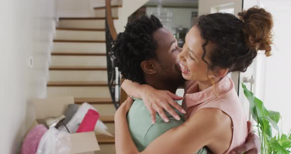 Happy biracial couple hugging with joy in new house