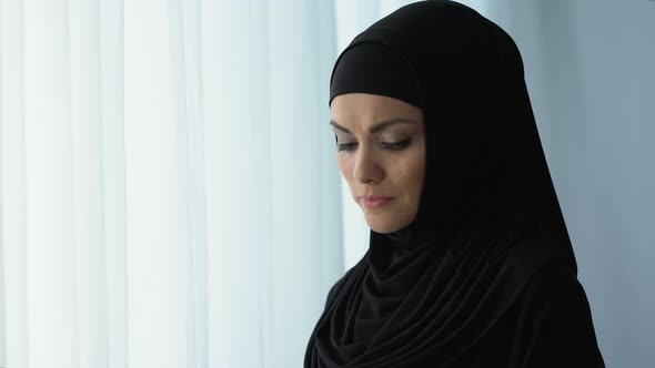 Pensive Arab Female Standing Near Home Window, Feeling Hurt, Disappointment