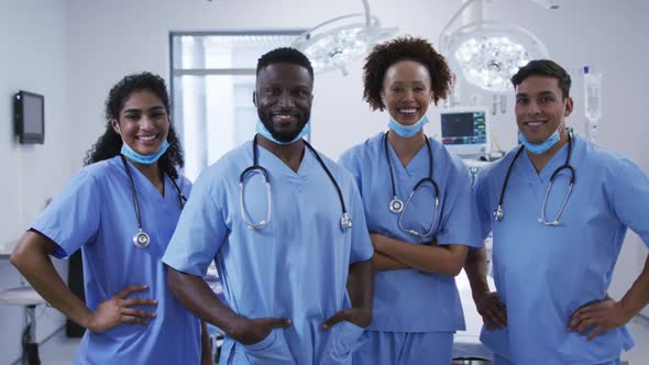 Portrait of diverse male and female doctors standing in operating theatre smiling to camera