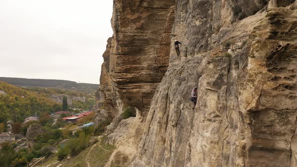 A Happy Female Rock Climber is Sitting on Top of a Mountain