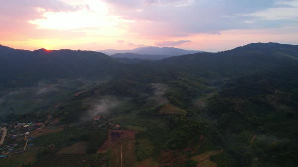 aerial view A drone fly over a rural area with mountains in the background at sunrise.