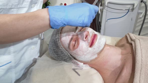 Happy Man Getting Facial Masks at Beauty Salon, Smiling with His Eyes Closed