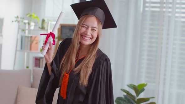 An Asian girl proudly shows her certificate. She is always smile on her graduation ceremony