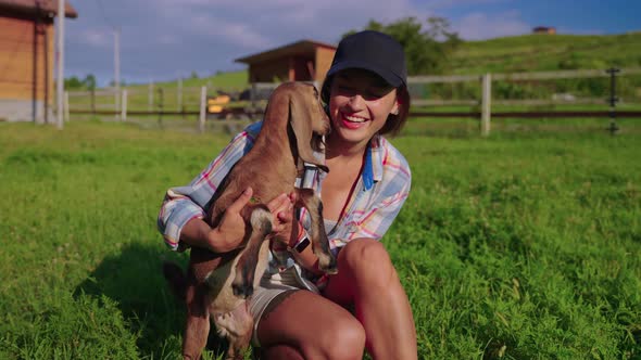 Farm Visitor is Playing with Cute Baby Goat in Livestock Farm Woman is Holding Little Boer Goat