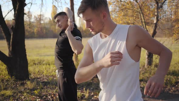 Two Caucasian Sportsmen Warming Up in the Autumn Park