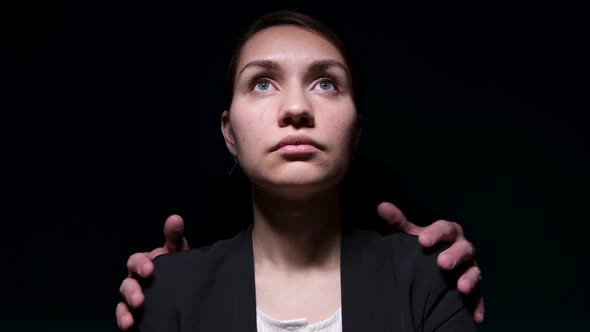 The hands of an unknown man lie on the shoulder of a young woman in a jacket