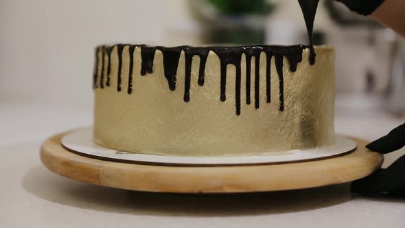 Chocolate icing on the cake. Golden cake covered with chocolate and cream. Cake decoration.