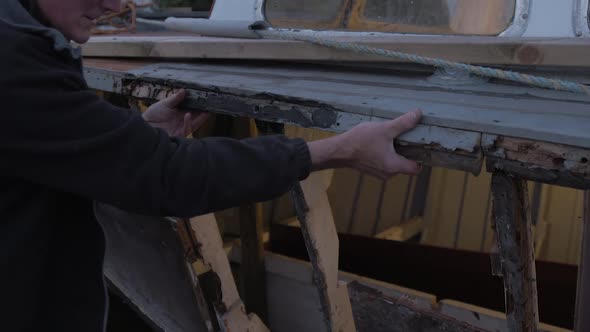 Carpenter working on eighty year old seaplane tender boat res rotten gunwale