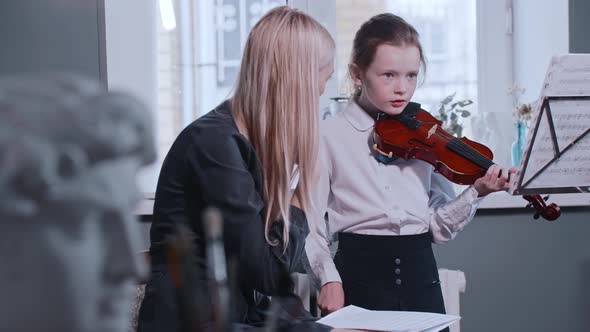 Young Woman Teacher Giving a Violin Lesson to a Little Girl in the Class