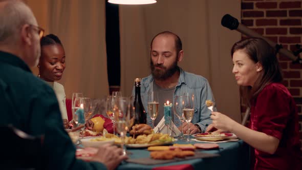 Joyful Multiethnic People in Dining Room Celebrating Winter Holiday with Traditional Home Cooked