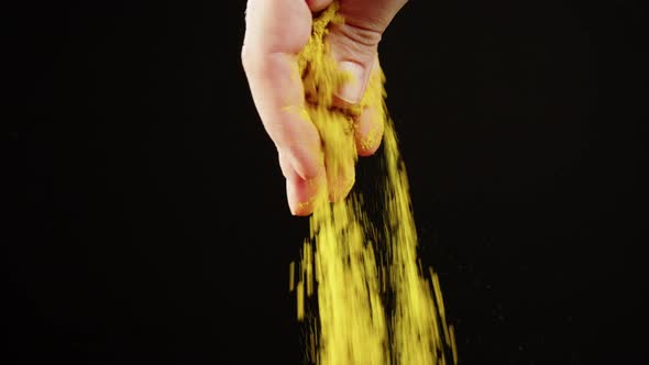 Adding Turmeric Powder to Dish on Black Background Using Seasoning and Flavors