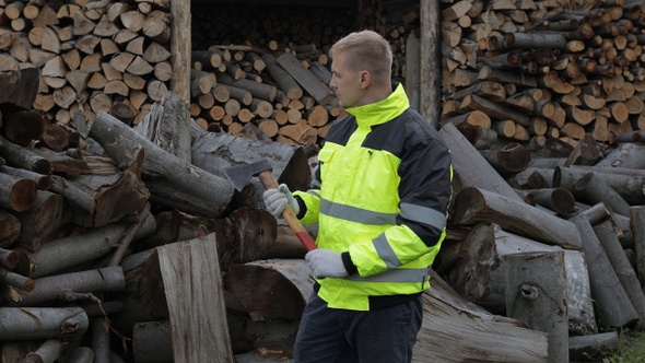 Lumberjack in Reflective Jacket. Man Woodcutter with Small Axe. Sawn Logs, Firewood Background