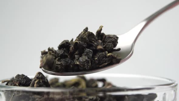 Dried rolled leaves of green premium tea in the form of pearls in a teaspoon