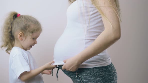 Little Girl Tries To Hide Under Pregnant Mother Tshirt