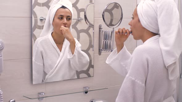 Woman Brushing Her Teeth in a Front of the Mirror