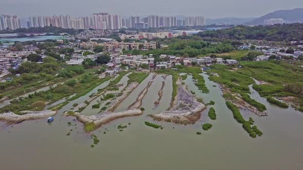 A dynamic aerial footage of the fishing village in Lau Fau Shan in the foreground and the big city o