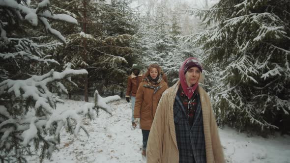 Young Tourists Walking through Winter Woods