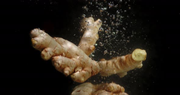 Pieces Fresh Ginger Root Falling Under the Water with Air Bubbles. 