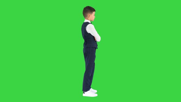 Confident Young Boy in Bow Tie and Vest Crossing His Arms and Putting Hands in His Pockets on a