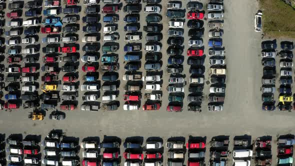 Top down aerial drone view over a scrapyard full of old cars.