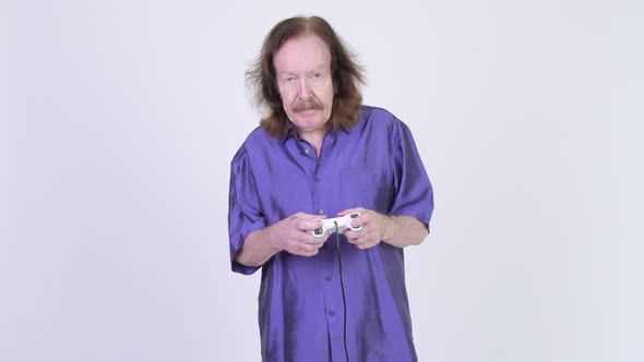 Stressed Senior Man with Purple Silky Shirt Playing Games and Losing