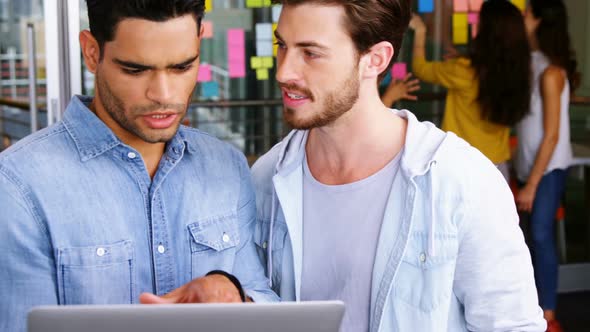 Male executives having discussion over laptop