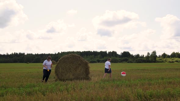 Funny Family with Their Son Run and Play Merrily Near the Haystack in the Field