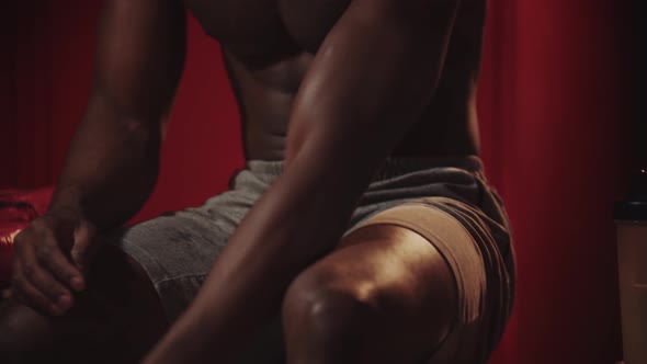 Black Young Man Boxer Putting on His Sneakers in a Locker Room