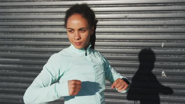 African american woman in sportswear stretching in street before exercising