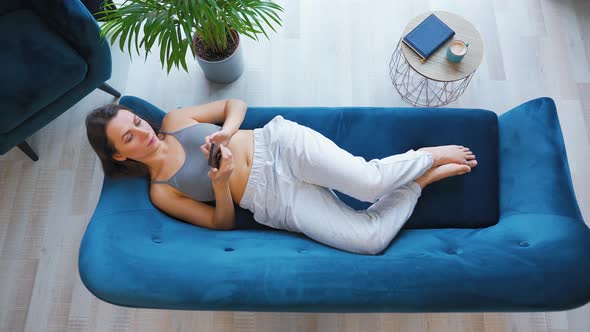 Overhead Shot of Happy Relaxed Woman Holding Smart Phone Using Mobile Apps Watching Funny Video