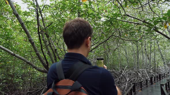 Man Traveler with Backpack Makes Video on Smartphone in Forest