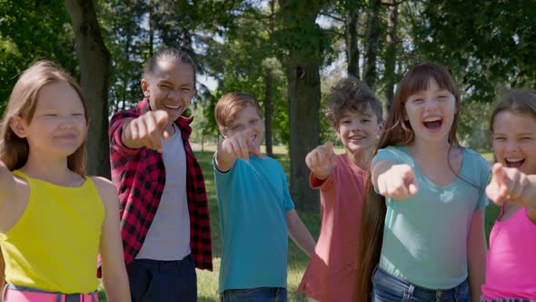 Medium Shot of Multiethnic Kids Point Finger at Camera and Laugh Outdoors